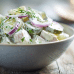 Fleischsalat in heller Schale mit Gurken und Kräutern