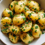 Kartoffelsalat mit Senf Vinaigrette in heller Schale, angerichtet mit frischen Kräutern